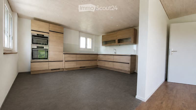 Modern kitchen with light wooden cabinets, stainless steel oven, and sleek countertops.