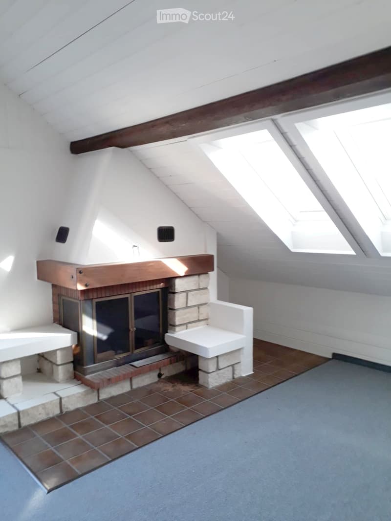 Loft-style room with exposed wooden beams, skylights, and a stone fireplace with built-in seating.