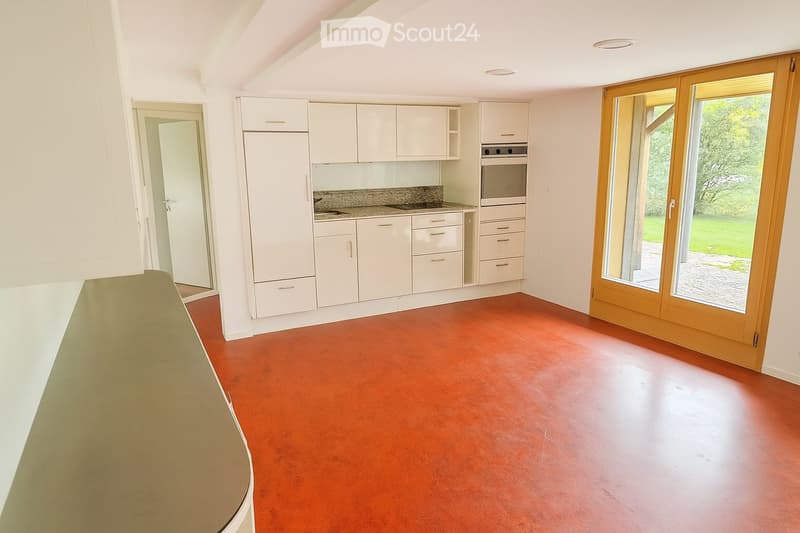 modern kitchen with white cabinets, gray countertop, red floor, double-door entrance, integrated oven and microwave, large windows