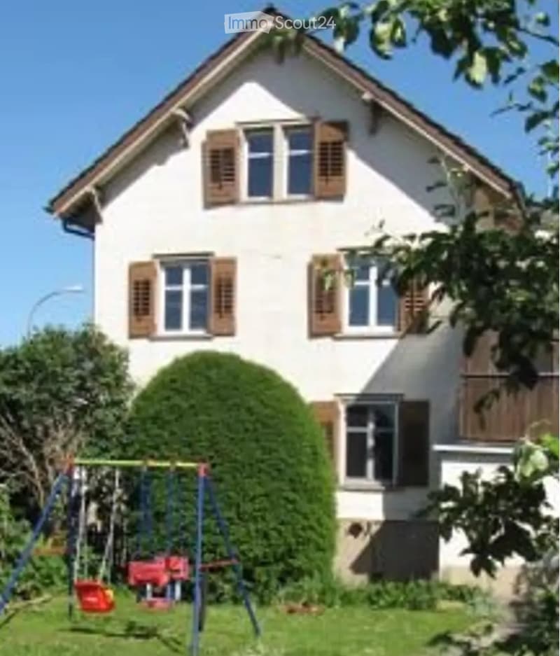 white 2 story house, brown shutters, red swing, green hedge, grass