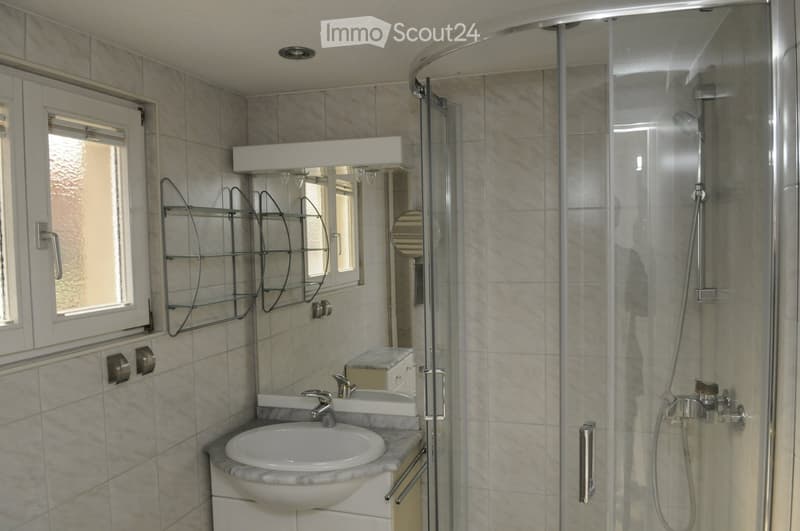White tiles, shower, sink, mirror with shelves, window