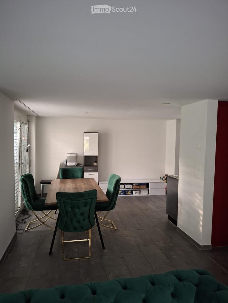 Dining area with a wooden table, green velvet chairs, a green sofa, and a small cabinet with a microwave.