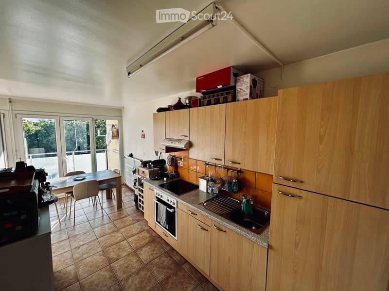 Bright kitchen with wooden cabinets, granite countertops, and tiled flooring. Features a dining area with a table and chairs, an oven, microwave, and sink.