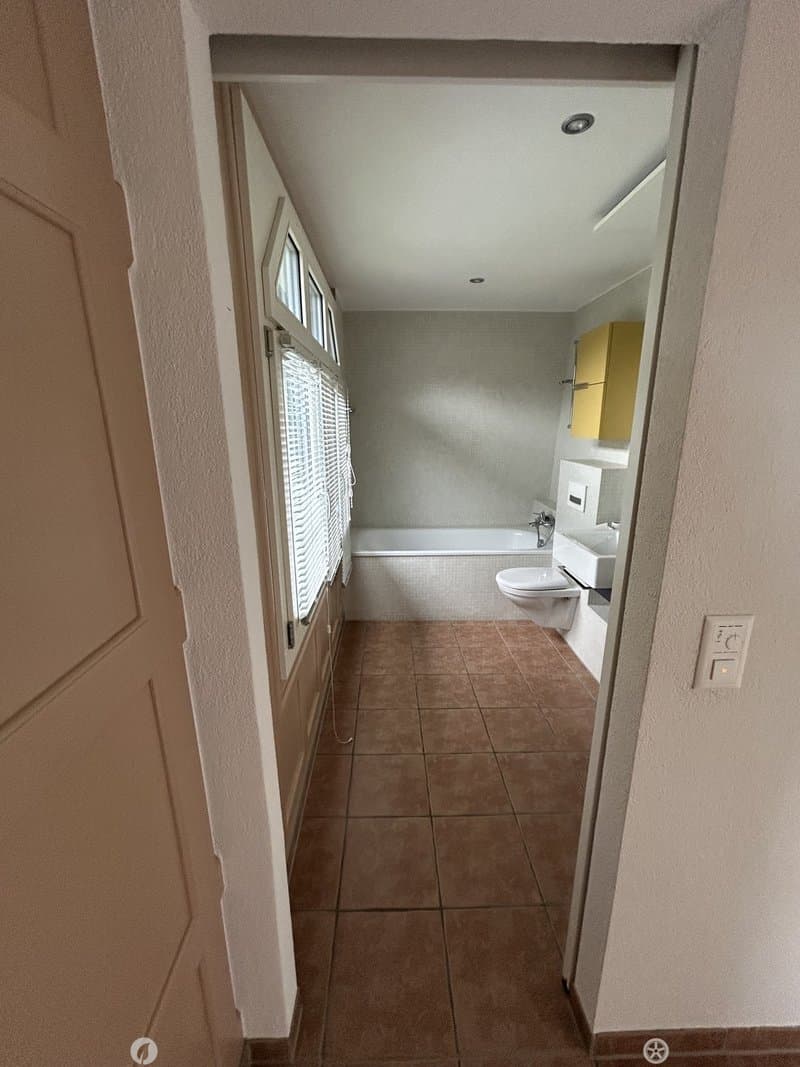 Bathroom with tiled floor, bathtub, toilet, sink, and a small yellow cabinet.