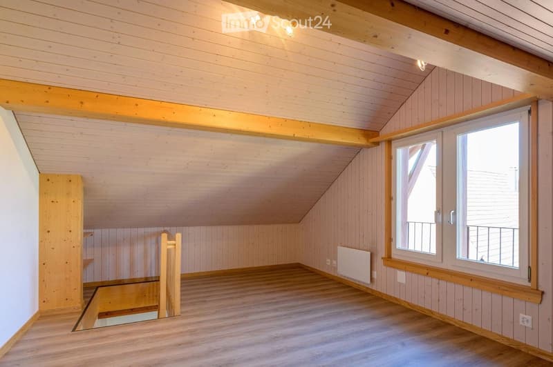 Empty room with wooden walls, ceiling, and floor, featuring a window with a view and a radiator below it.