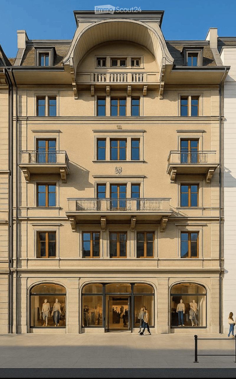 A multi-story building with beige facade, arched windows, and balconies. The ground floor features large glass storefronts with mannequins displayed inside.