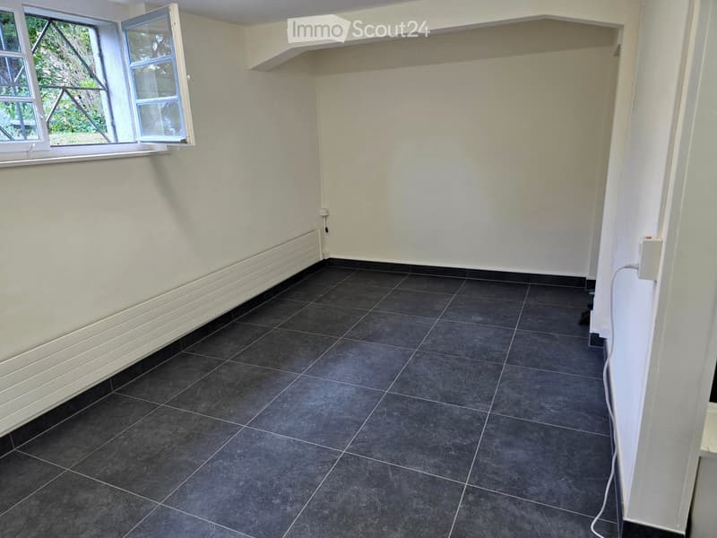 Empty room with dark grey tiled floor, white walls, and a window with white frame and glass panes.