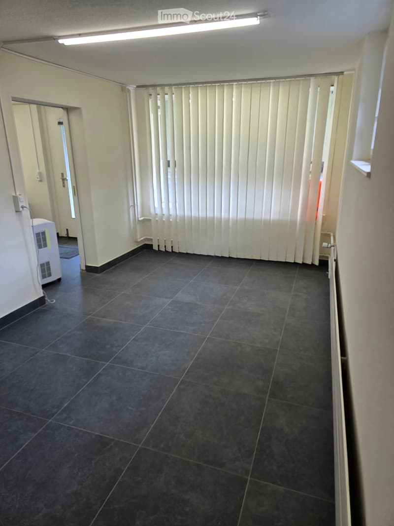 Empty hallway with dark tiled floor, white walls, and vertical blinds covering a window. An air conditioning unit is visible on the left side.