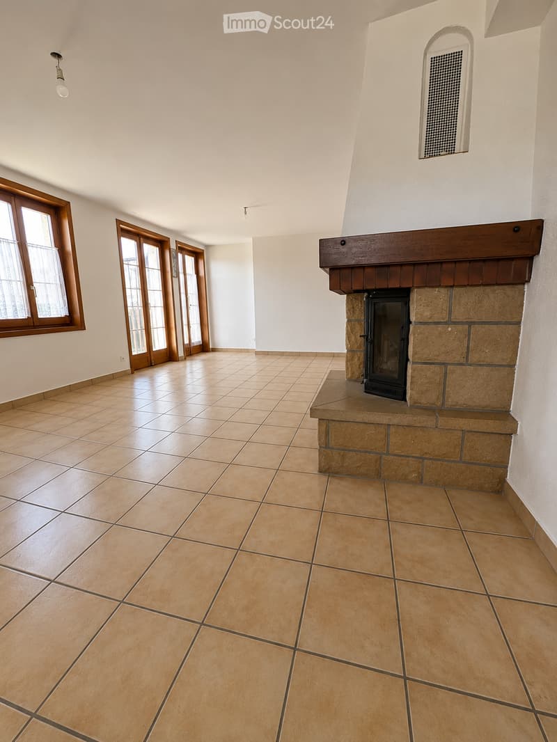 Empty room with tiled floor, fireplace, large windows, and wooden doors.
