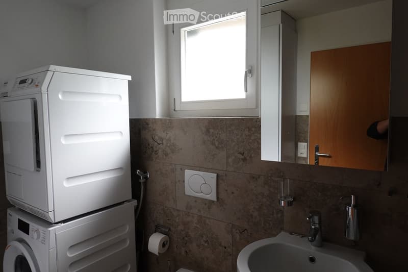 Bathroom with a washing machine and dryer, a sink, and a mirror.