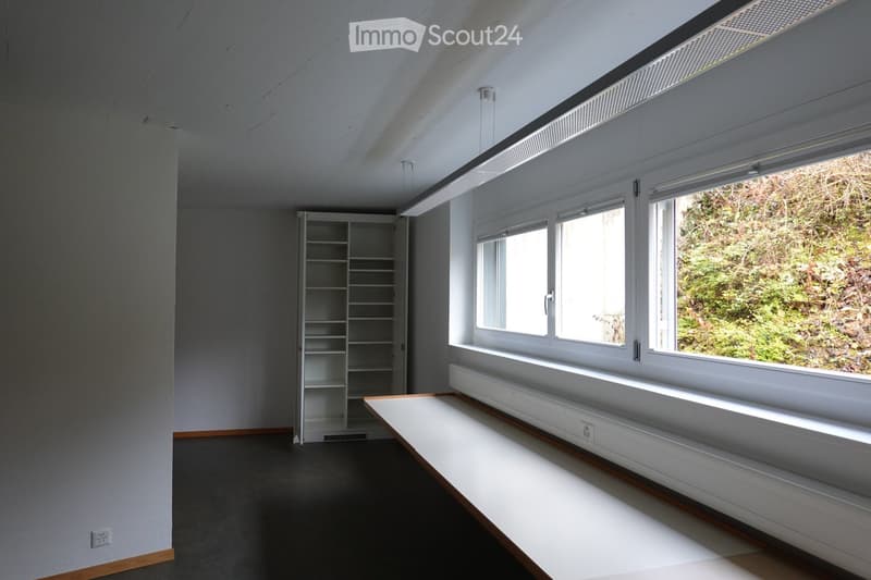 Completely empty room with white walls, black floor, a white shelf, and a bench under the window.