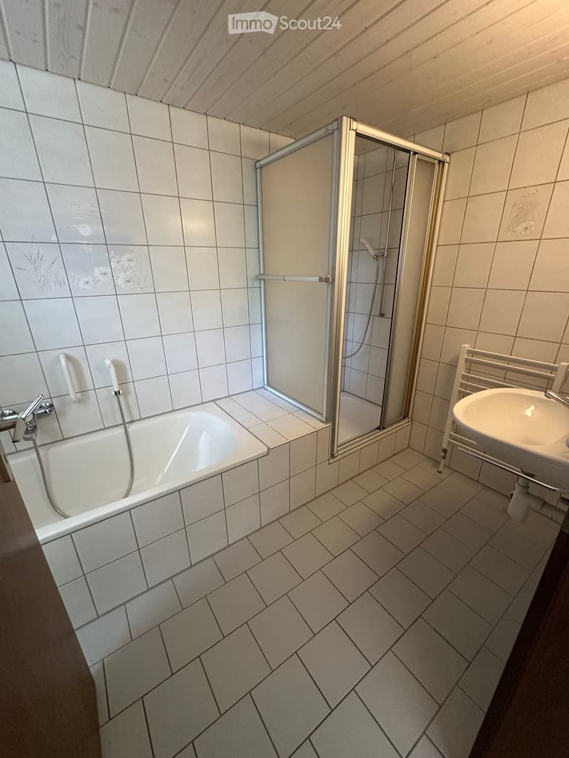 Bathroom with a bathtub, shower stall, and sink. The walls are tiled with a floral pattern, and the floor has a diamond-patterned tile design.