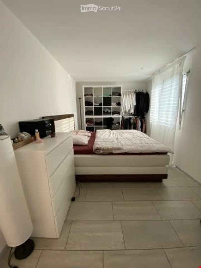 white walls, white tiled floor, white chest of drawers, double bed, clothes rack, white curtains