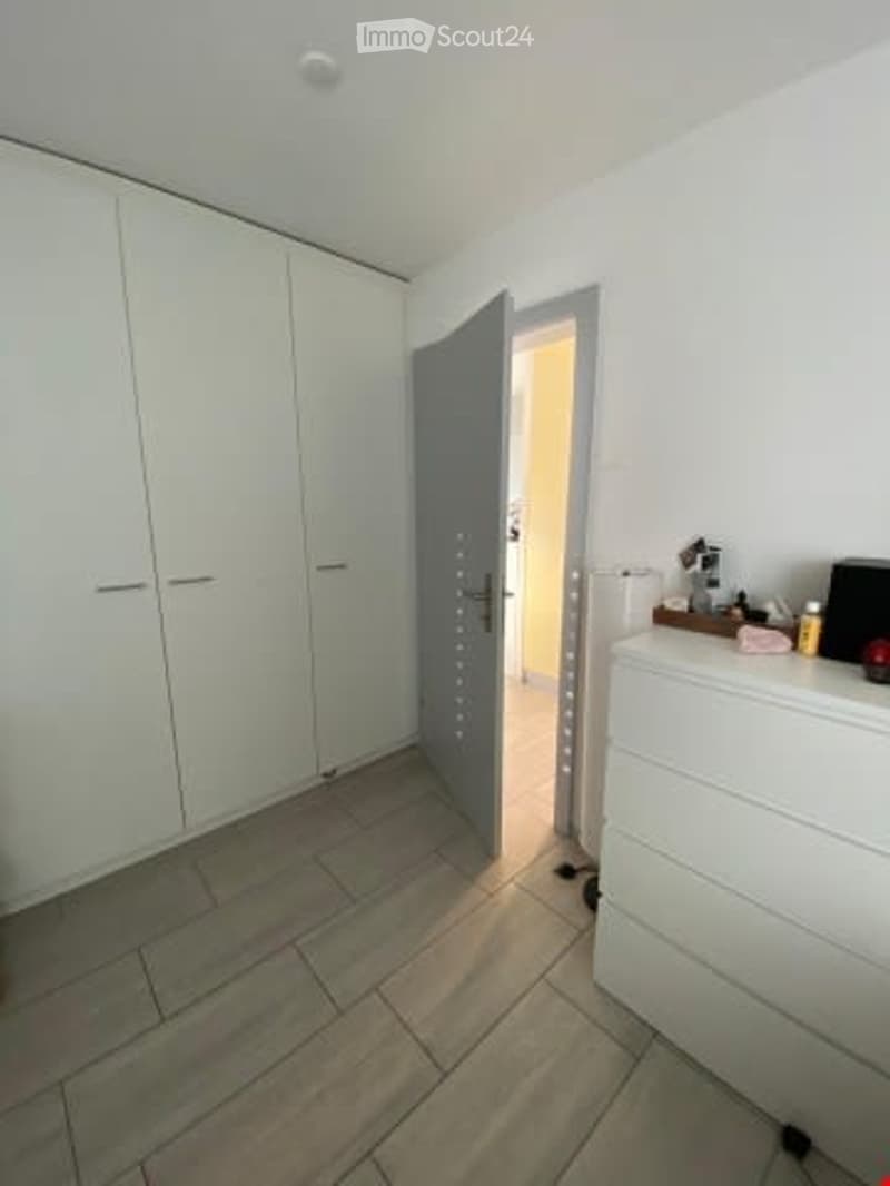 large room with walk-in closets, open door to another room, white tile flooring