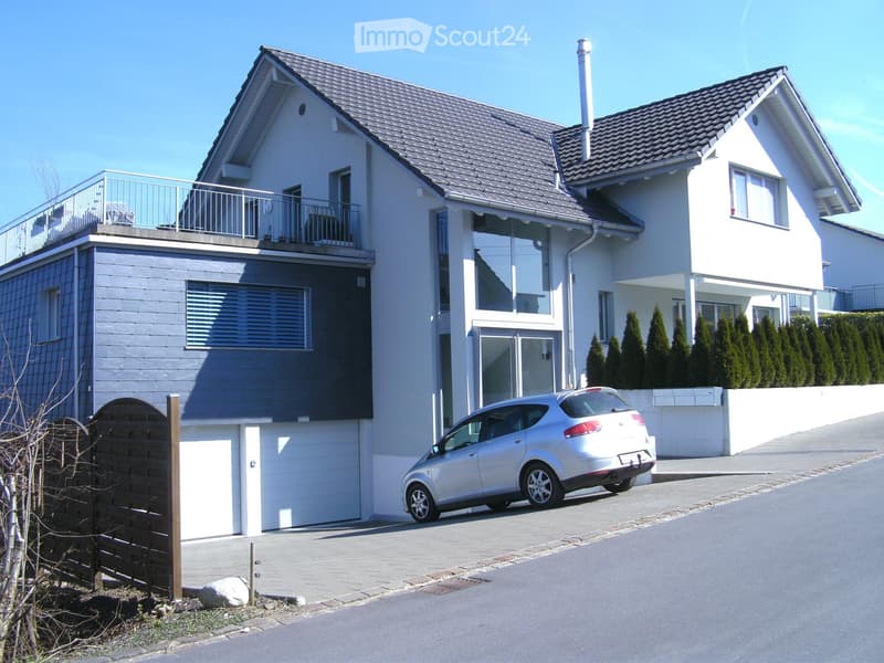 2 story modern house, blue wall, gray roof, white garage, car parked in front, terrace