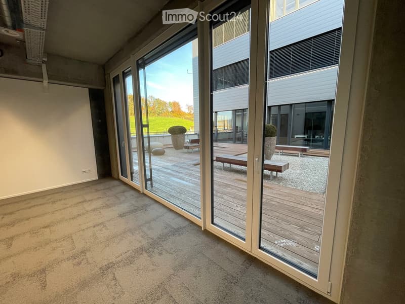 Empty room with carpeted floor, large glass sliding doors leading to a wooden deck and outdoor seating area.