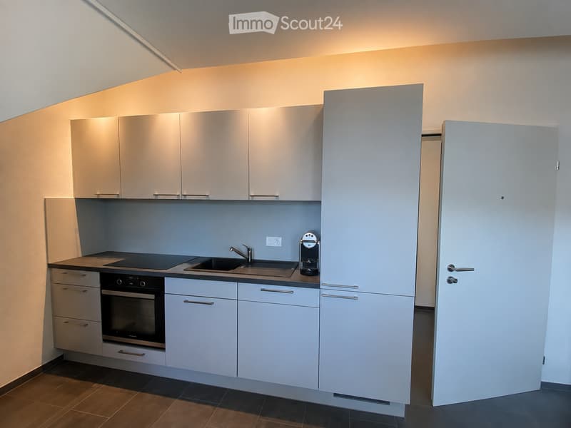 Modern kitchen with light-colored cabinets, a sink, an oven, and a coffee maker on the counter.