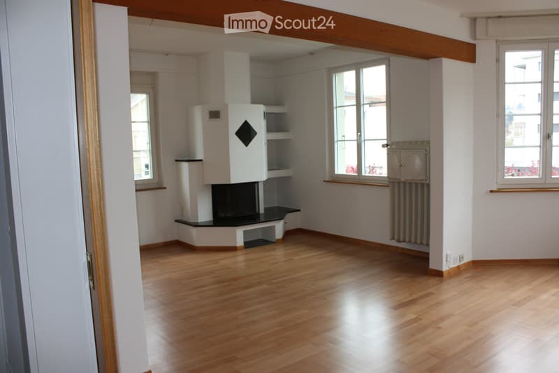Empty room with wooden flooring, white walls, and a fireplace with built-in shelving. Windows provide natural light.