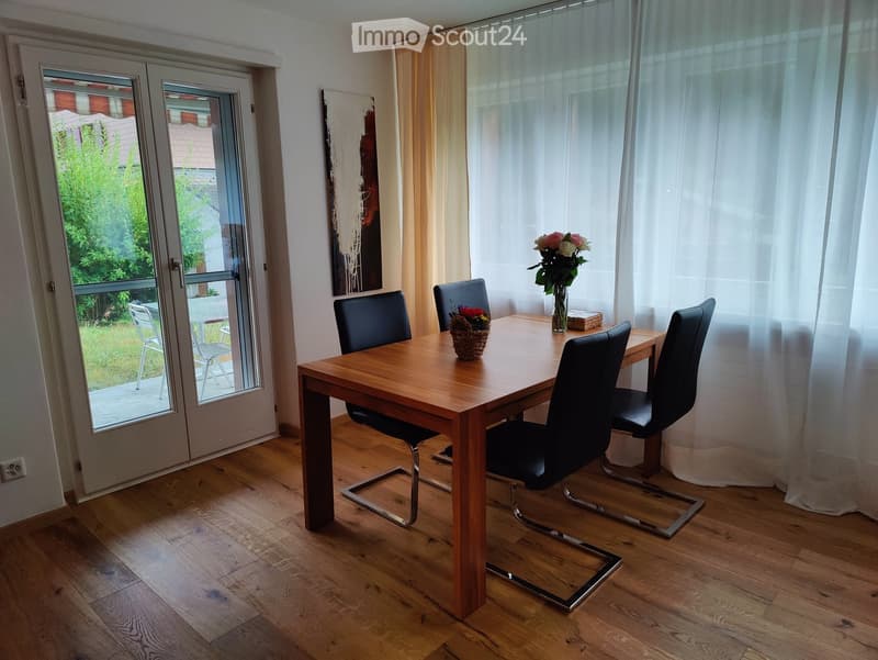 wooden table, black chairs, flower vase, door leading to balcony