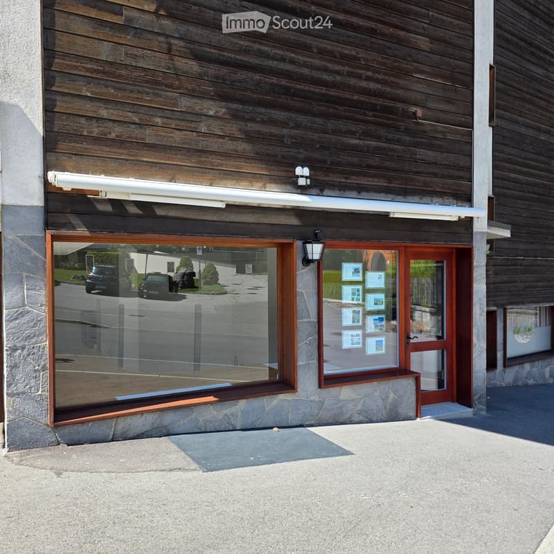 Facade of a building with wooden paneling, large glass window, and a wooden door with posters displayed on it.