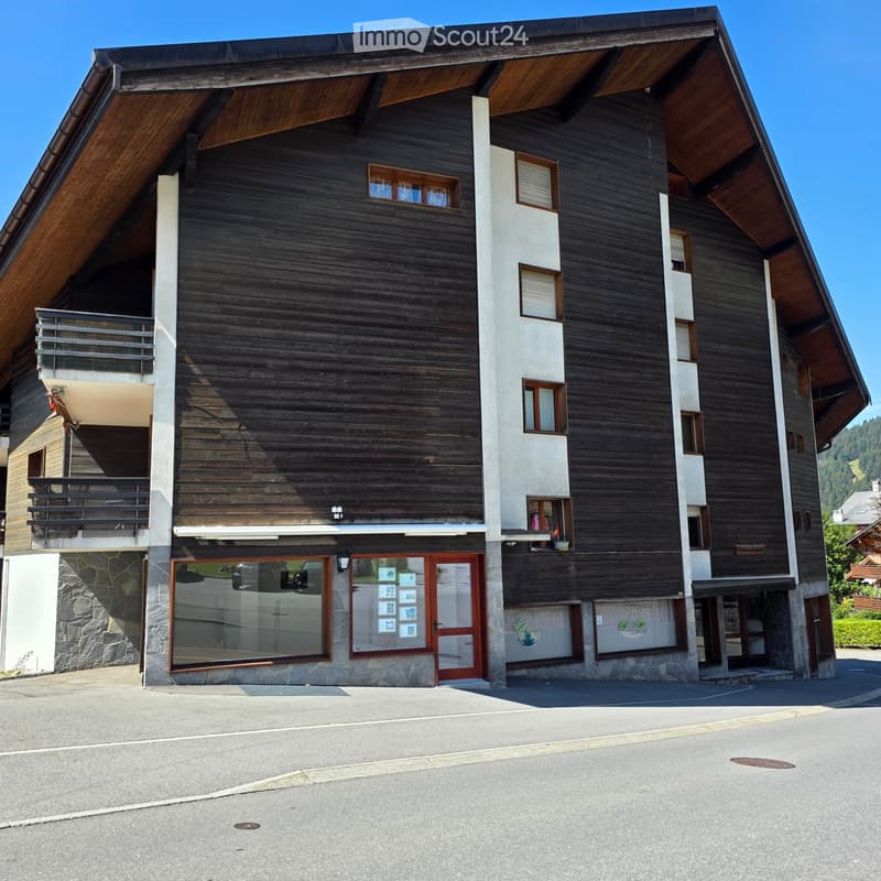 Modern two-story building with dark wooden facade, white concrete accents, large windows, and balconies.