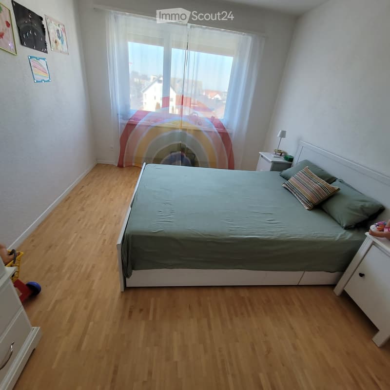 Bedroom with wooden flooring, a bed with green bedding, nightstand with lamp, and a small toy visible near the bed.