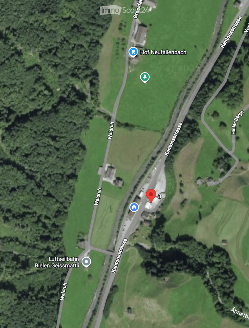 Aerial view of a rural area showing a building labeled '3' near a road intersection surrounded by green fields and trees.