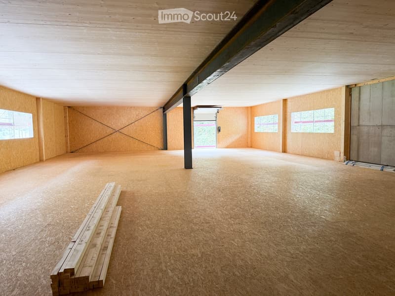 Empty room with wooden flooring, exposed wooden ceiling beams, and natural light from windows. No furniture or furnishings present.