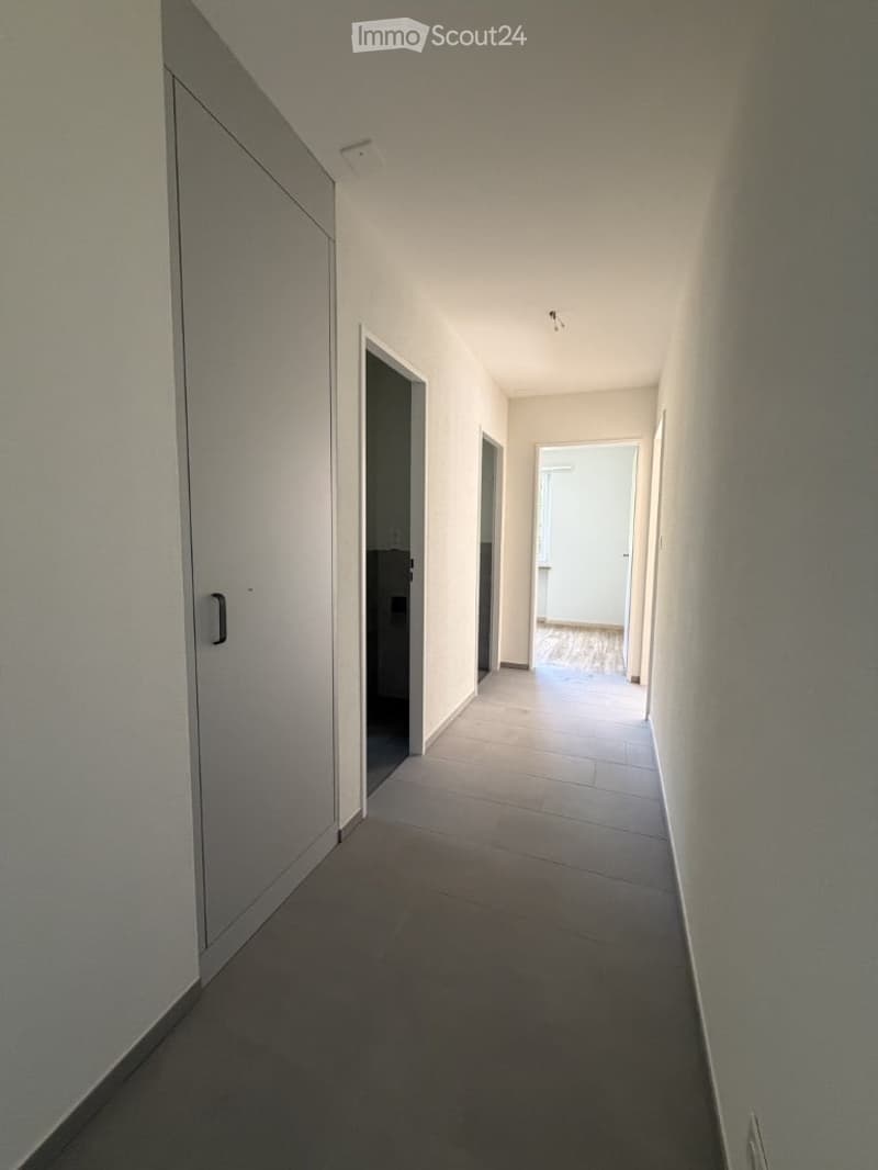 Empty hallway with tiled floor, white walls, and several doors leading to other rooms.