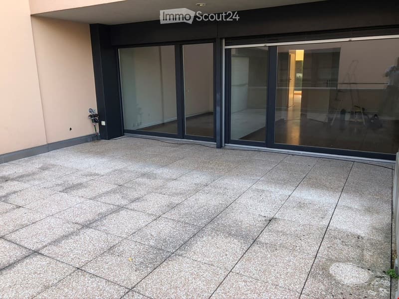 Empty balcony with large sliding glass doors leading to an interior space, tiled floor, and modern design.