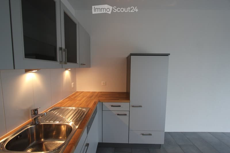 Modern kitchen with white cabinets, wooden countertops, and a stainless steel sink.