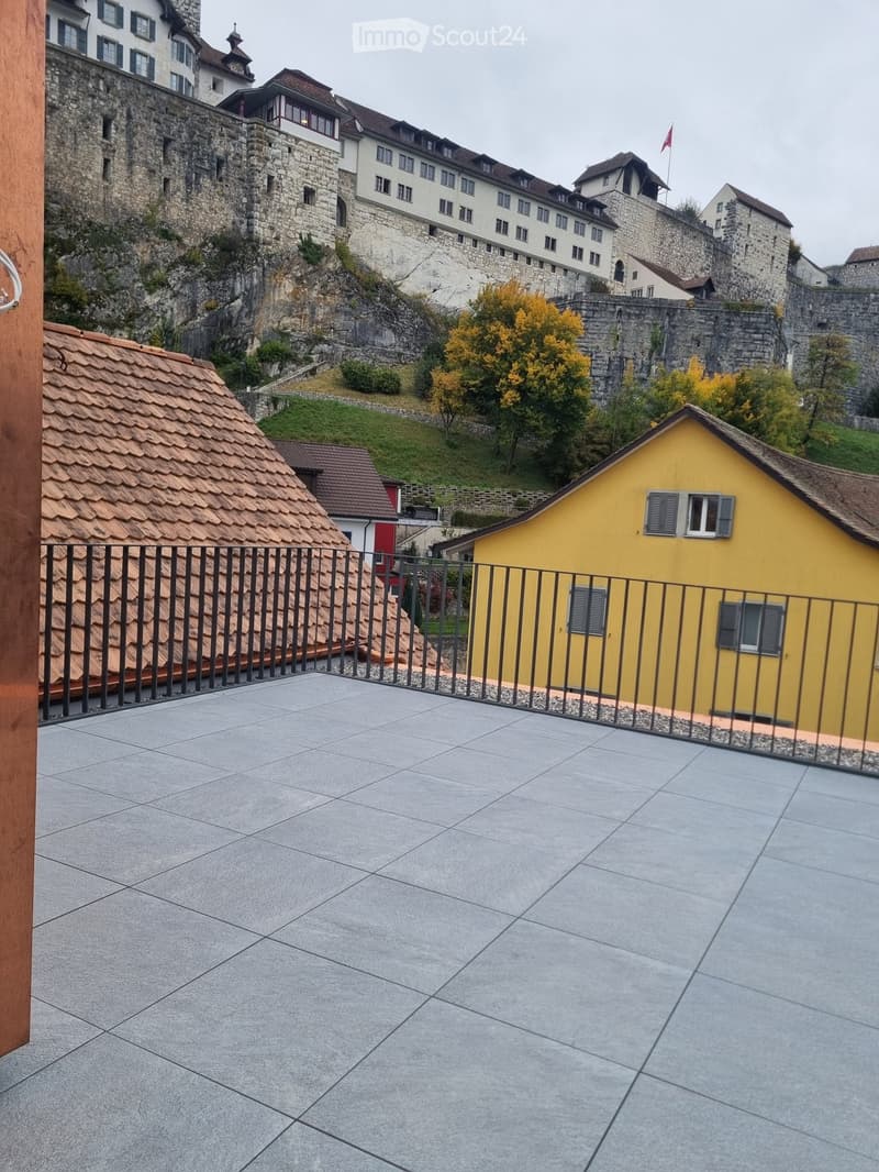 House with stone walls and tiled terrace, overlooking castle and valley.