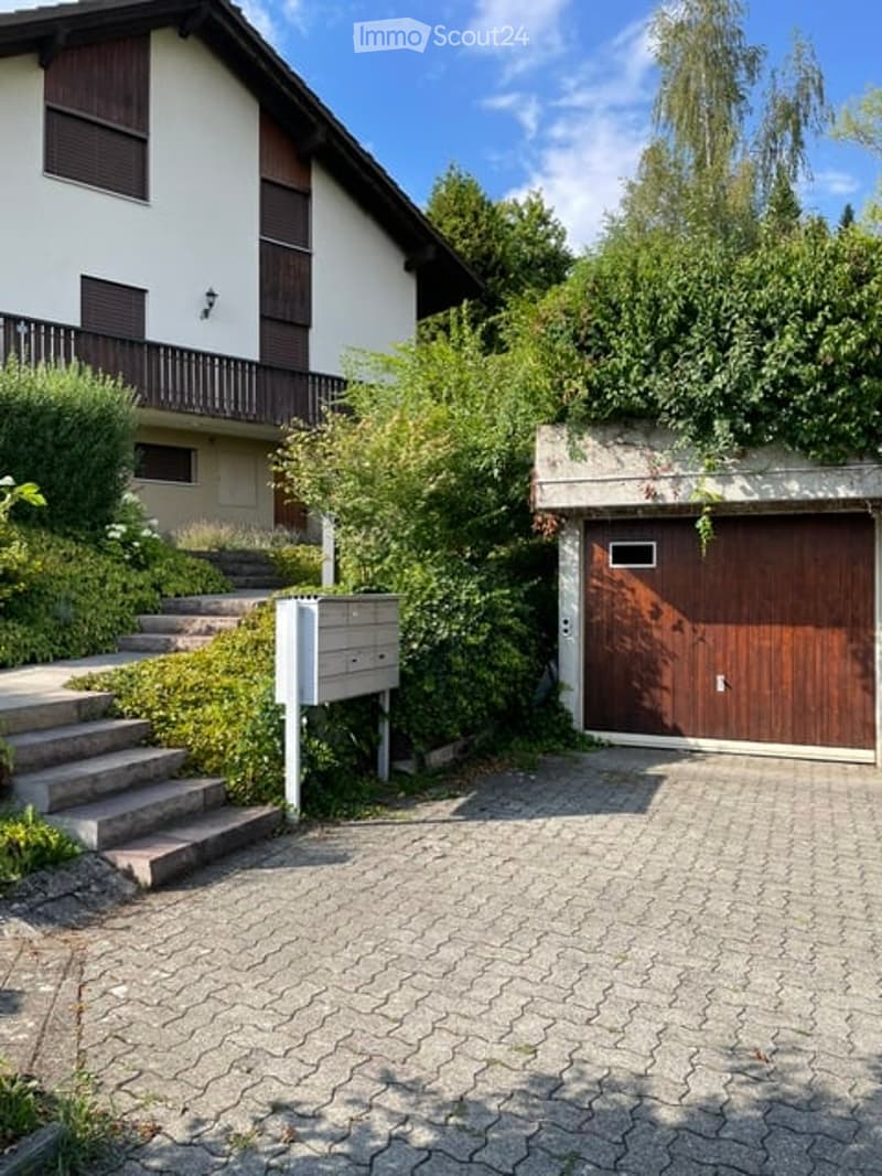 Two-story house with a garage, raised ground floor, and steps leading up to the entrance.