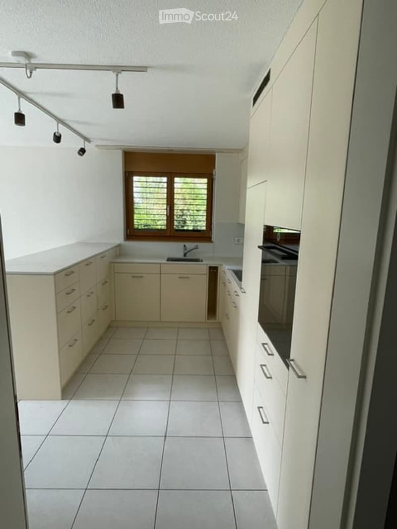 Modern kitchen with white cabinets, tiled floor, and stainless steel appliances.