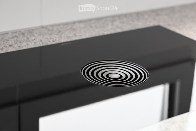 Modern black induction cooktop with a sleek, minimalist design, featuring a circular cooking zone.