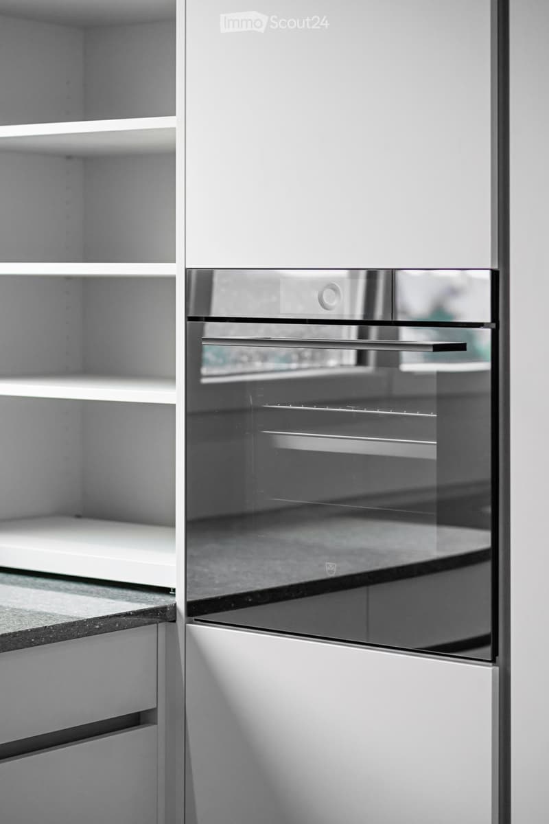 Modern kitchen with sleek white cabinets and a built-in stainless steel oven.