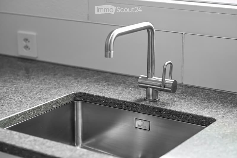 Modern kitchen sink with a sleek stainless steel faucet and a granite countertop.