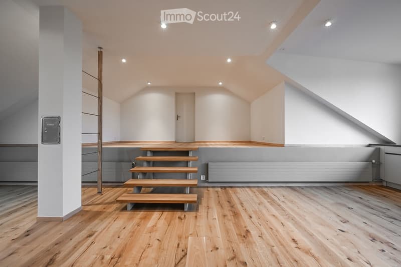 Empty room with wooden flooring, white walls, recessed lighting, and a staircase leading to an upper level.