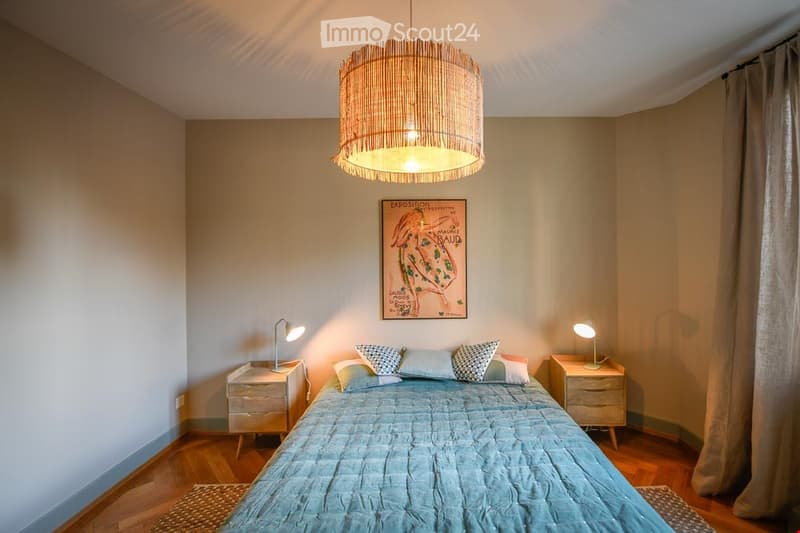 Cozy bedroom with a large bed, nightstands, lamps, and a decorative picture frame on the wall.