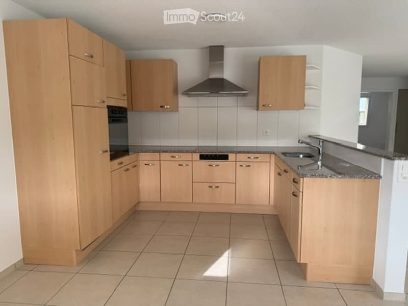 Modern kitchen with light wooden cabinets, stainless steel appliances, and granite countertops.