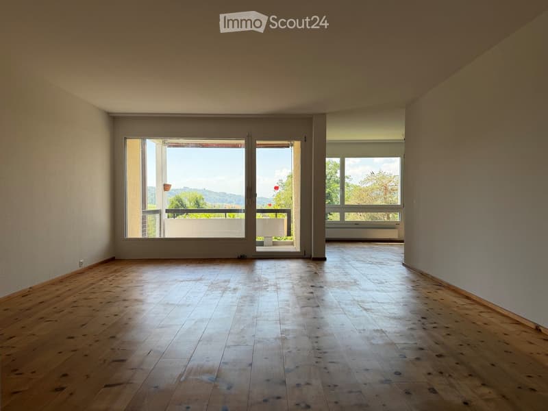 Empty room with wooden flooring, large windows, and a view of the outdoors.