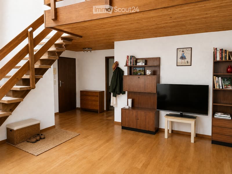A modern living room with wooden flooring, a staircase leading to an upper level, a television on a stand, a bookshelf, a small table, a wooden cabinet, a wicker basket, and a coat hanging on the wall.