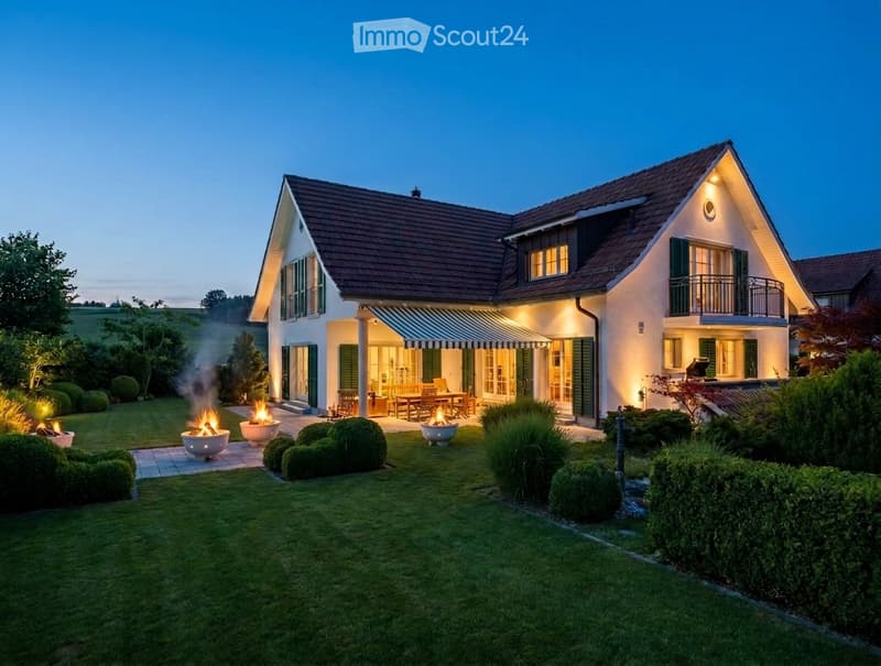 Two-story house with a modern design, featuring a well-maintained lawn, outdoor seating area, and fire pits.