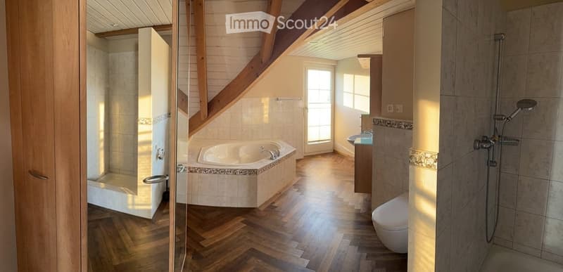 Modern bathroom with wooden flooring, a bathtub, a toilet, a sink, and a shower area with a glass enclosure.