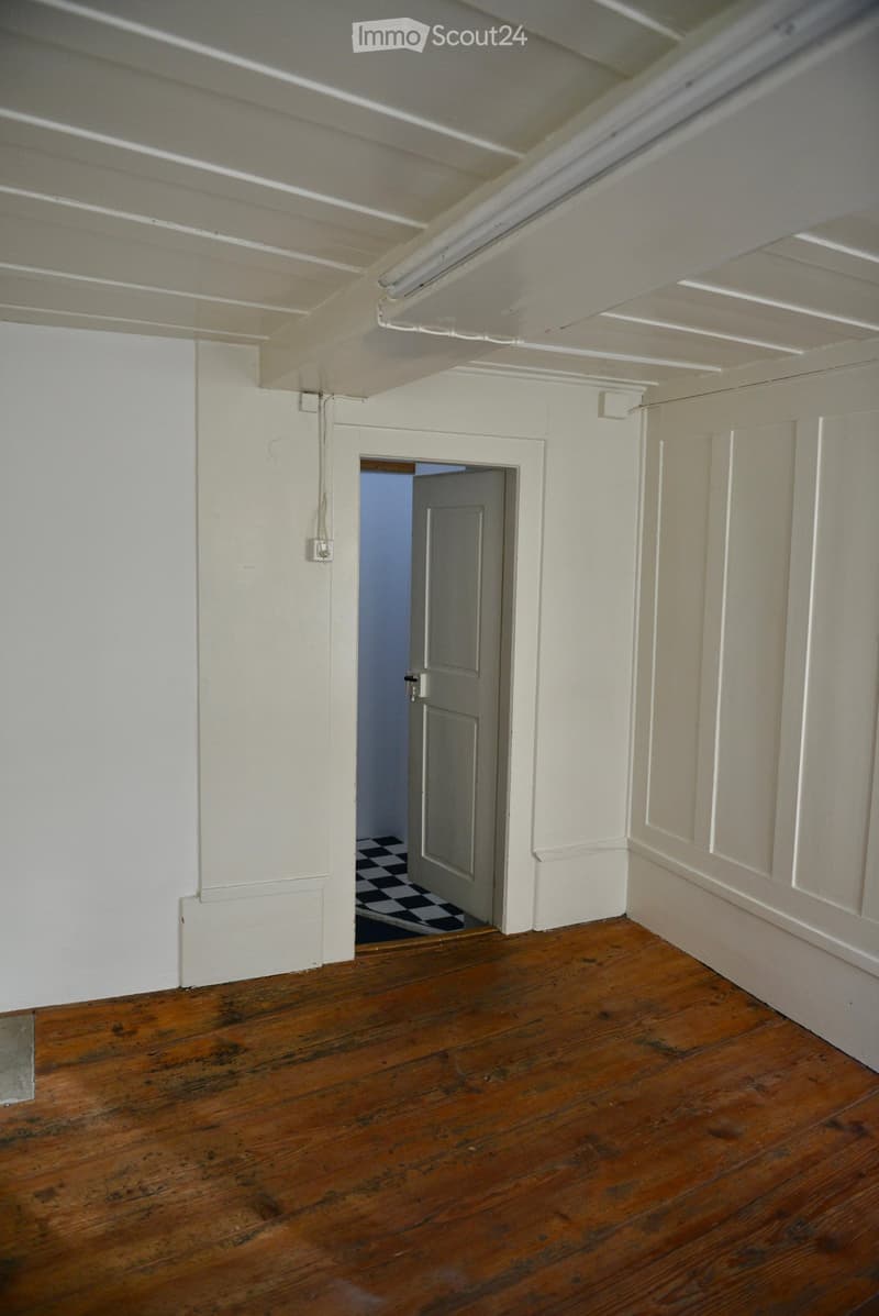 Empty room, wooden floor, white walls, open door, white ceiling, tiled doormat