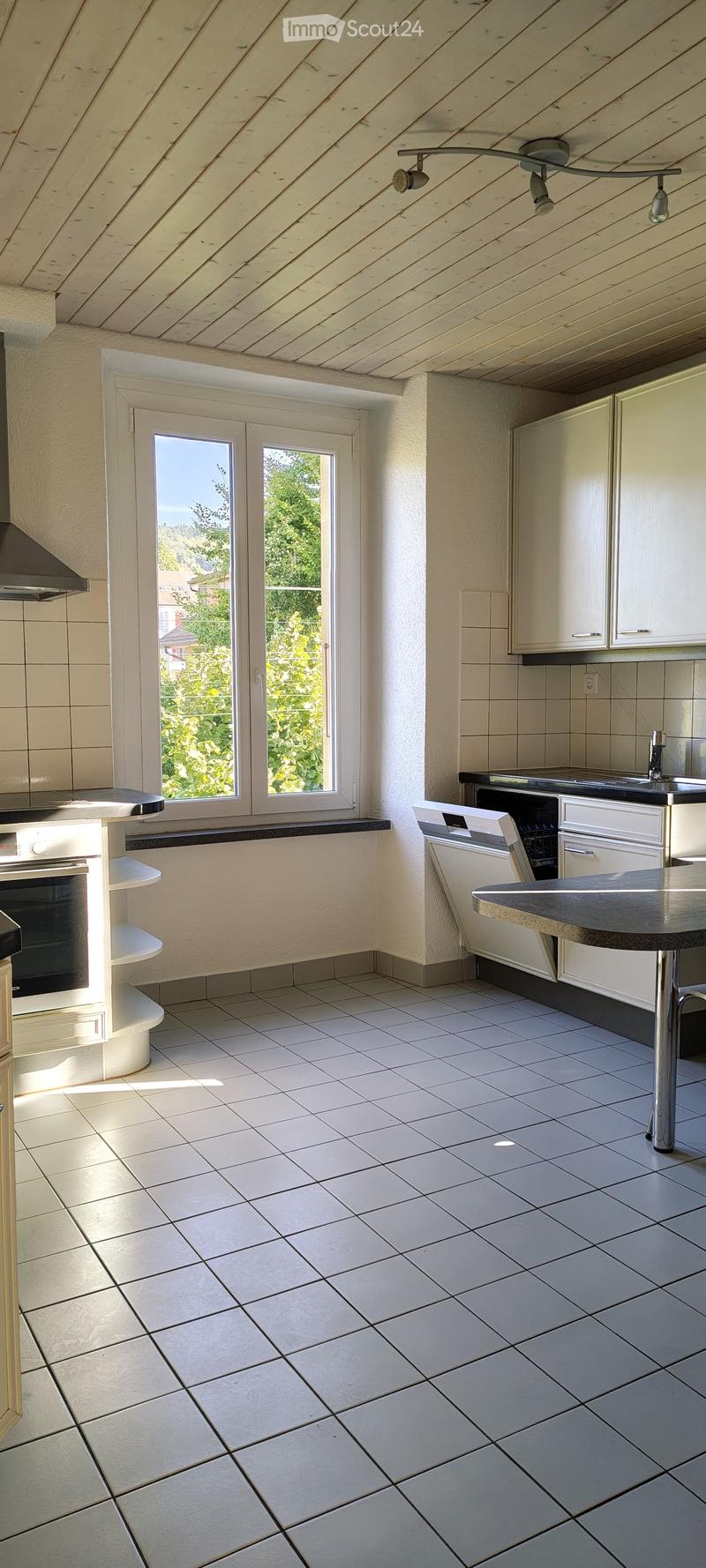 Modern kitchen with white tiled floor, white cabinets, stainless steel appliances, and a central island with a sink and dishwasher.