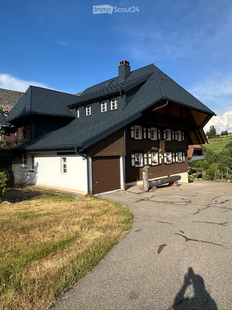 Two-story house with dark roof, white and brown exterior, garage, and windows with flower boxes.