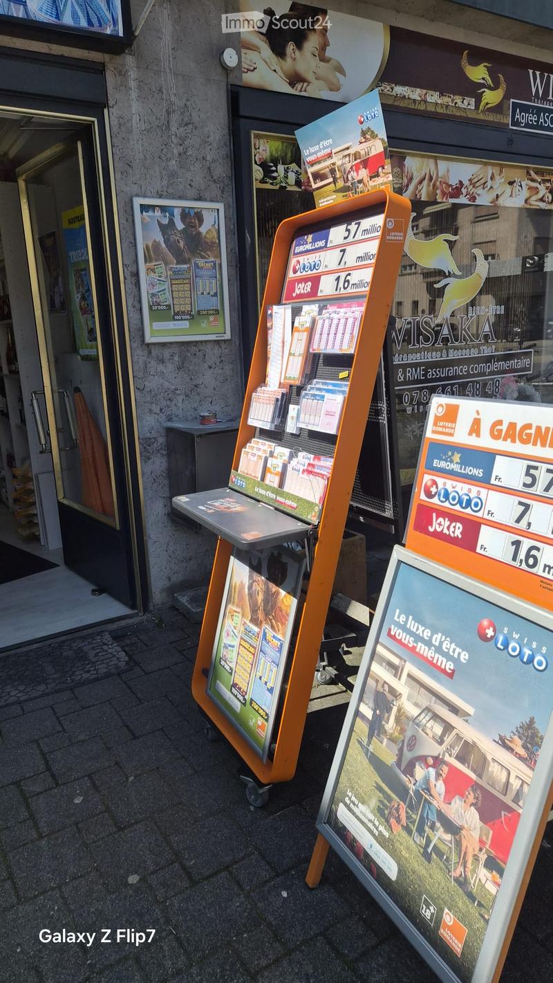 Outdoor display with lottery tickets and promotional posters, including a large orange stand with lottery ticket options and a poster advertising a lifestyle theme.