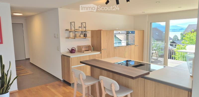 modern kitchen, white counters, wooden cabinets, black appliances, breakfast bar, balcony, scenic mountain view