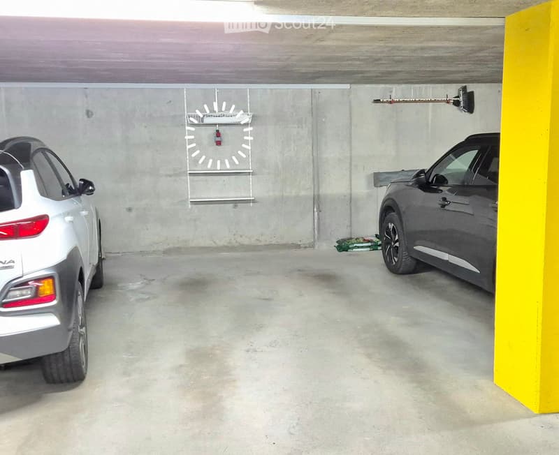 underground parking with two cars, yellow barrier pillar, clock